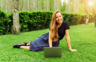 Güzel kız freelancer dizüstü bilgisayar ile çimenlerin üzerinde