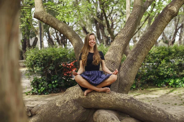 Девушка медитирует на дереве в парке — стоковое фото