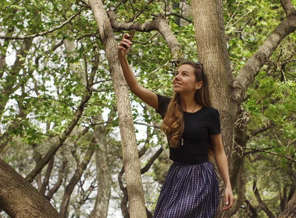 Девушка с телефоном в лесу ищет связь — стоковое фото