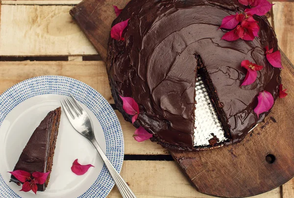 Ahşap zemin üzerine kesilmiş bir parça ile çikolatalı kek — Stok fotoğraf