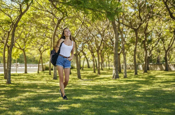 Девушка с рюкзаком прогулка в парке — стоковое фото