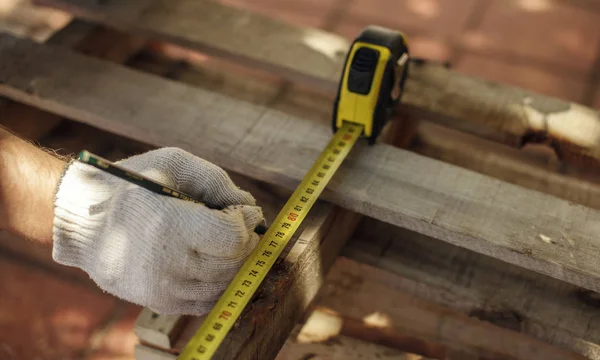 Ölçü birimi ile birlikte kalem ve cetvel, marangozluk yapan erkek