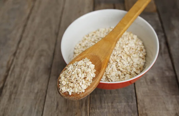 Tahta kaşık, rustik arka plan içinde Kuru yulaf ezmesi