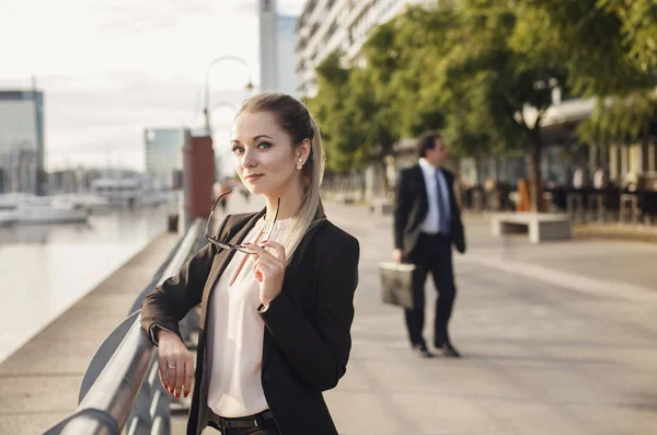 Mujer de negocios sonriendo al aire libre con la figura del hombre detrás —  Fotos de Stock