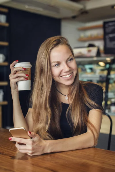 Elinde bir cep telefonu ile kahve içme kadın — Stok fotoğraf