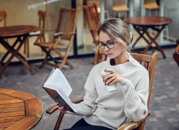 Güzel genç kadın bir fincan kahve ile bir kitap okuma