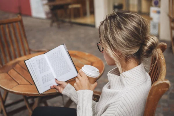 Kadın bir fincan kahve ile bir kağıt kitap okuma