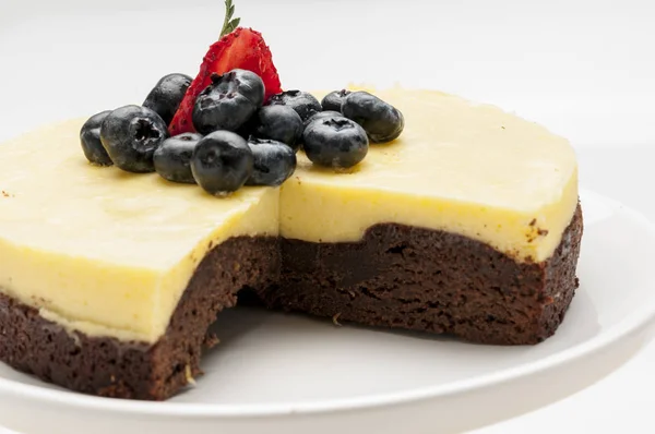 Çikolata ve maracuya kek dekore böğürtlen ve çilek kahverengi masa örtüsü pasta zanaat üzerinde beyaz tabakta caffe çay infüzyon catering sosyal etkinlikler düğün doğum günü için