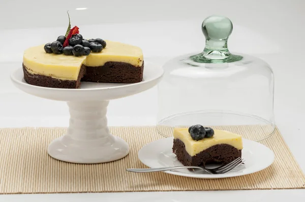 Çikolata ve maracuya kek dekore böğürtlen ve çilek kahverengi masa örtüsü pasta zanaat üzerinde beyaz tabakta caffe çay infüzyon catering sosyal etkinlikler düğün doğum günü için