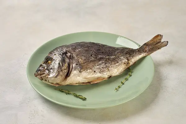 Gebackener Dorado-Fisch auf einem grünen Teller — Stockfoto