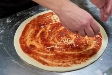 Mutfaktaki şef pizza hazırlıyor.
