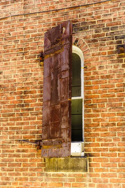 Volet semi-fermé très ancien avec vieille fenêtre rouillée sur un bâtiment en brique — Photo