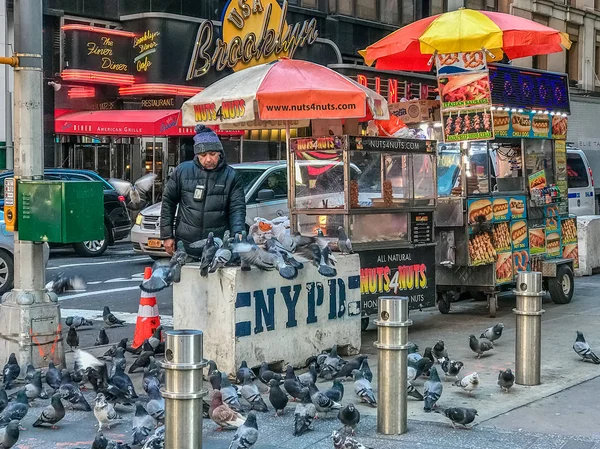 Times Square Manhattan NY US - February 5 Street food cart in Manhattan seller is feeding pigeons — Stock Photo, Image