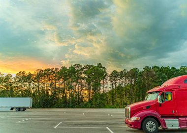 Georgia Usa 'daki ziyaretçi merkezi ve dinlenme alanı yaz günbatımının arka planına karşı gökyüzünde beyaz, turuncu, mavi ve koyu bulutlar ve ağır kamyonlar,