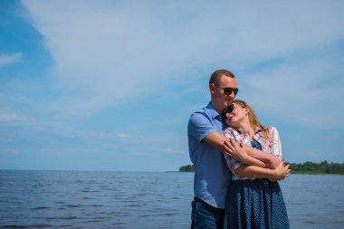 nehre ayakta birbirimizi, mavi gökyüzü arka plan, güneşli bir gün, geniş açı, uzun beyaz couds kucaklayan bir sevgi dolu bir çift