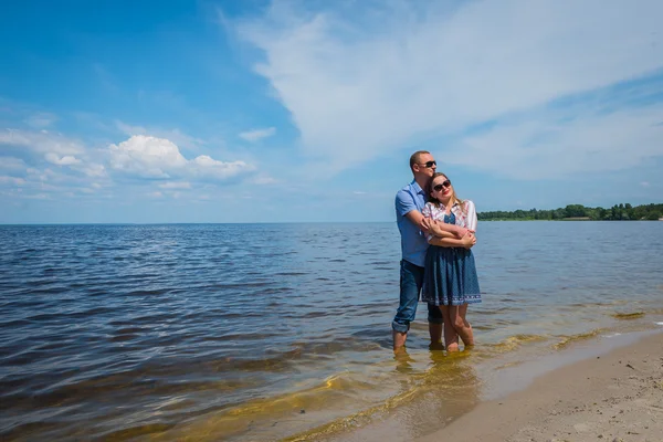 Un couple amoureux debout dans la rivière, s'embrassant, ciel bleu en arrière-plan, journée ensoleillée, grand angle, longs couples blancs — Photo