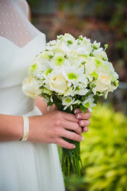 Beyaz güller ve yeşil krizantem düğün buket onun elinde tutan bir gelin yapılmış 