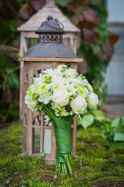A menyasszony az esküvői csokor fehér rózsával, zöld krizantém Vintage fa lámpás és moss a háttérben készült — Stock Fotó