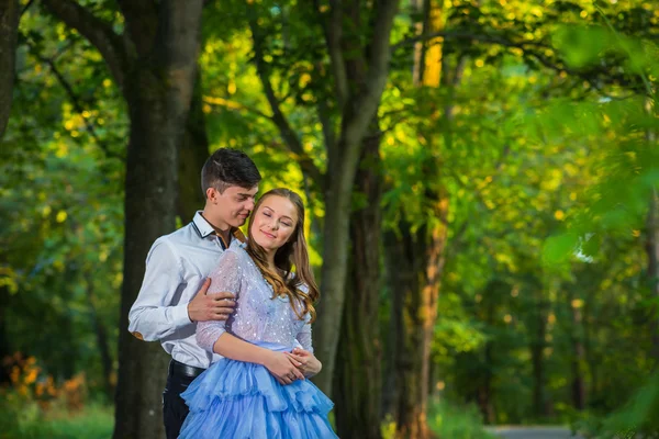 A love story couple, in love, together in the forrest park,  girl in a beautiful violet dress, sunny evening, summer, holding each other — Stock Photo, Image