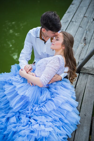 Un couple d'histoire d'amour, amoureux, ensemble dans le parc forestier, sur le pont en bois, fille dans une belle robe violette, soirée ensoleillée, été, eau verte sur le fond — Photo