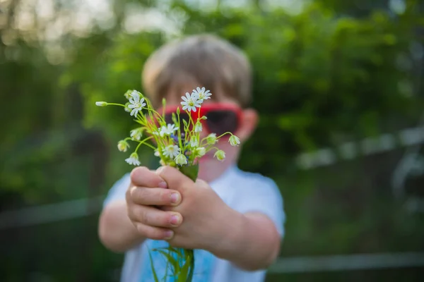 花、花を示すことを持っている焦点のない少年 ストック画像