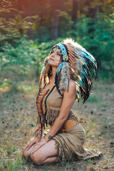 Mujer joven vestida en un estilo indio en el bosque en la cucaracha india con plumas —  Fotos de Stock