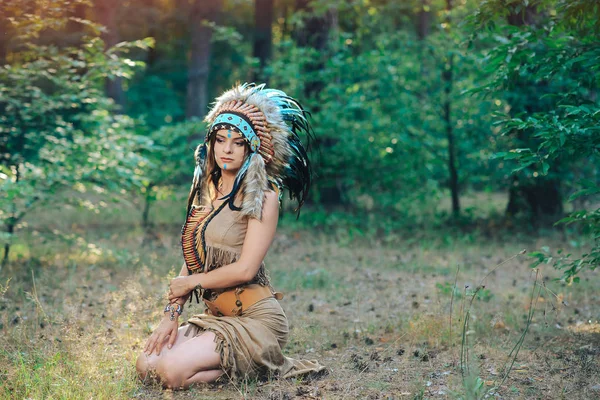 Schöne Mädchen im Anzug des amerikanischen Indianers sitzt im Wald in der Kakerlake — Stockfoto