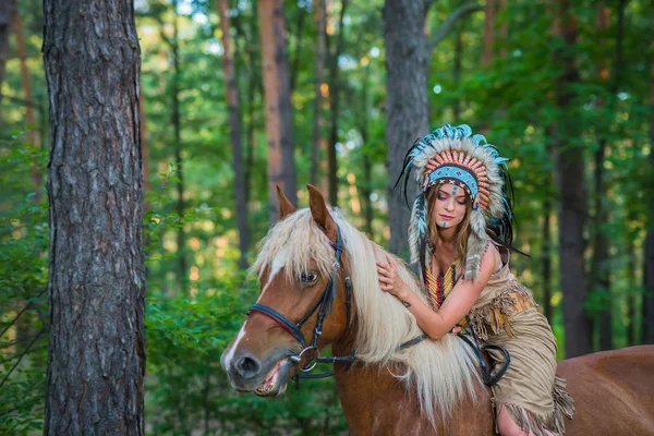 Bella ragazza in una tuta dell'indiano americano che cavalca un cavallo, fauna selvatica Immagine Stock