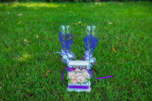 Stemware de casamento, óculos na grama com a caixa para anéis em tema violeta — Fotografia de Stock