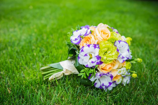 Wedding bouquet on the green grass, madd from roses and eustoma - orange and voilet colors — Stock Photo, Image
