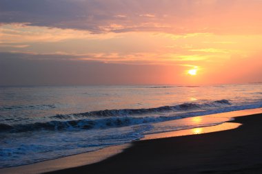 Günbatımı sahil, dalgalar ve kum