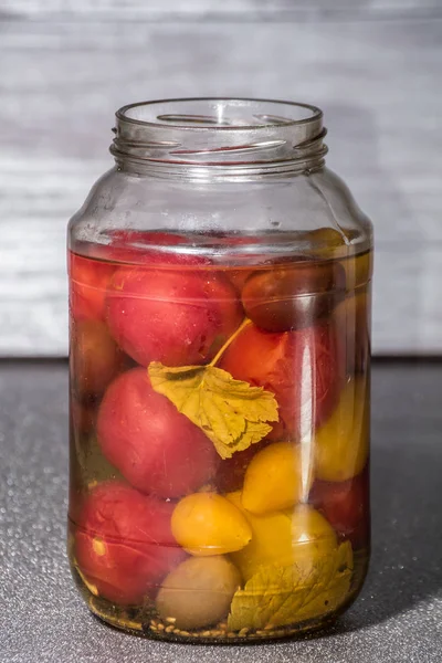 Fresh tomatoes. Canned tomatoes. tomatoes in a glass jar on a gray table. Concept from alfaphoto