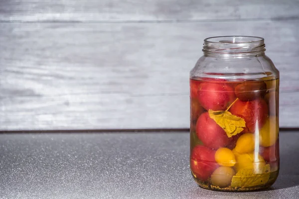 Fresh tomatoes. Canned tomatoes. tomatoes in a glass jar on a gray table. Concept from alfaphoto