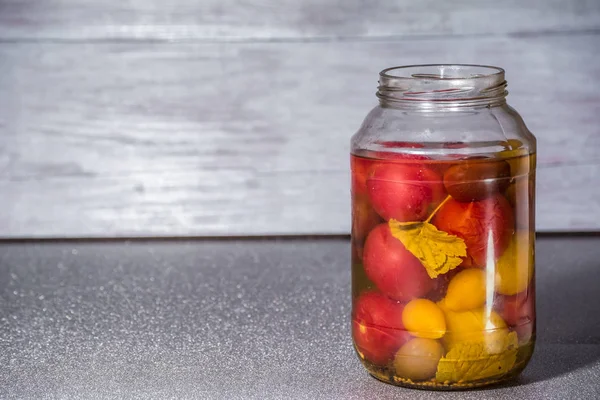 Fresh tomatoes. Canned tomatoes. tomatoes in a glass jar on a gray table. Concept from alfaphoto