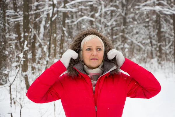 Porträtt av en trevlig äldre kvinna i vinter snö trä i röd kappa — Stockfoto