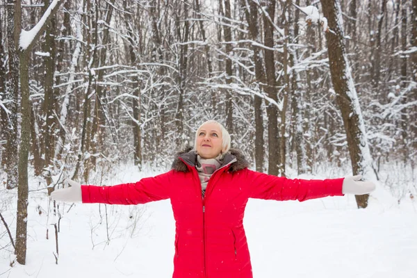 Porträtt av en trevlig äldre kvinna i vinter snö trä i röd kappa — Stockfoto