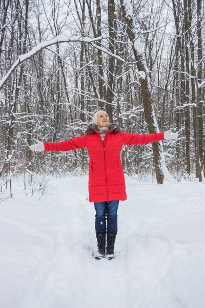 Porträtt av en trevlig äldre kvinna i vinter snö trä i röd kappa — Stockfoto