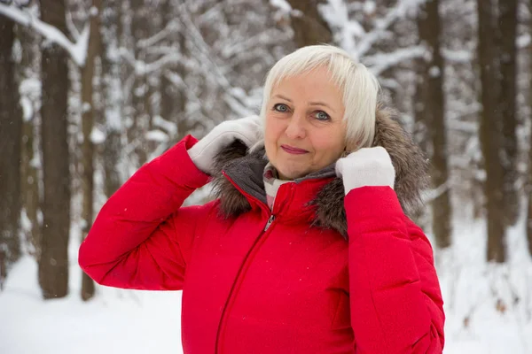 Portret ładne kobiety wyższego szczebla w drewno snow Zima w czerwonym płaszczu — Zdjęcie stockowe