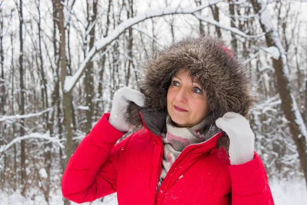 Porträtt av en trevlig äldre kvinna i vinter snö trä i röd kappa — Stockfoto