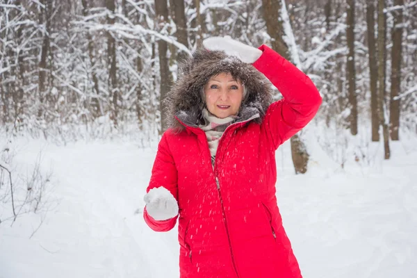 Senior gumman kastar snöboll i trä i röd kappa — Stockfoto