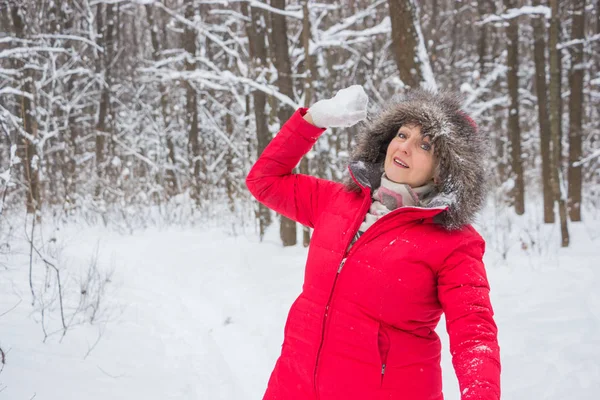 Senior gumman kastar snöboll i trä i röd kappa — Stockfoto