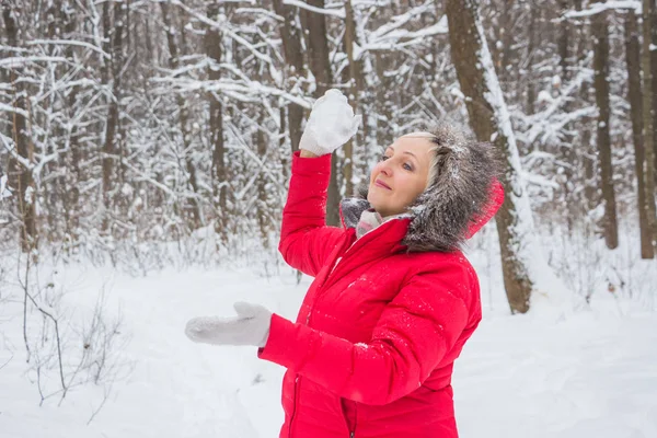 Senior gumman kastar snöboll i trä i röd kappa — Stockfoto