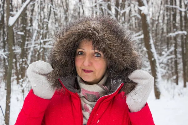 Portrait of a nice senior woman in the winter snow wood in red coat — Stock Photo, Image