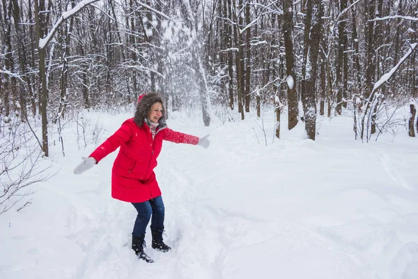 Senior stara kobieta wyrzuca śnieg w drewnie w czerwonym płaszczu — Zdjęcie stockowe