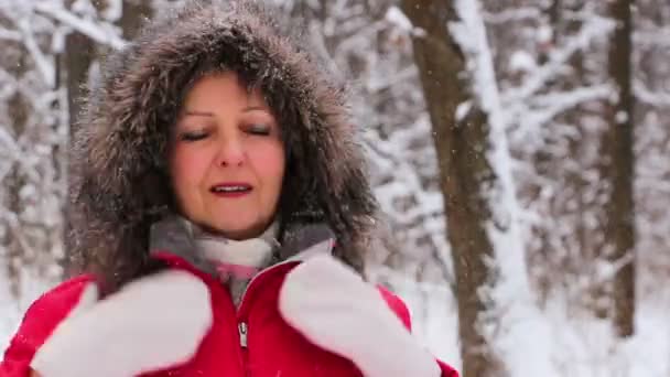 Attractive senior woman in the winter snow wood in red coat having fun — Stock Video
