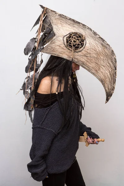 Siyah tüyleri ve beyaz arka plan gölgeler ile karga kafasına cadı ya da şaman halloween Kostüm giymiş güzel kız