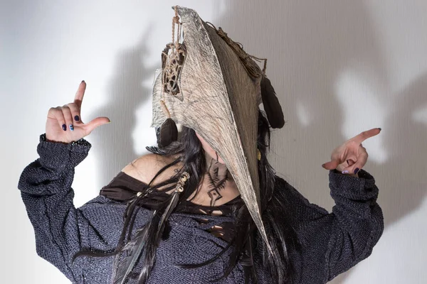 Siyah tüyleri ve beyaz arka plan gölgeler ile karga kafasına cadı ya da şaman halloween Kostüm giymiş güzel kız