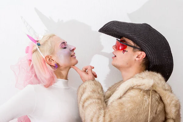 Cute pink unicorn girl with cowboy in fur in love. Close-up portrait of a couple. Halloween cosplay costumes