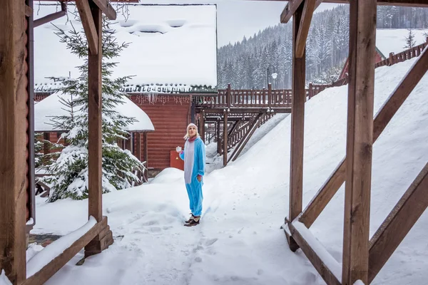 Kız mavi, pembe tek boynuzlu at pijama kigurumi önünde ahşap açık kahve içme kar dağlarda Kayak rapordaki evler