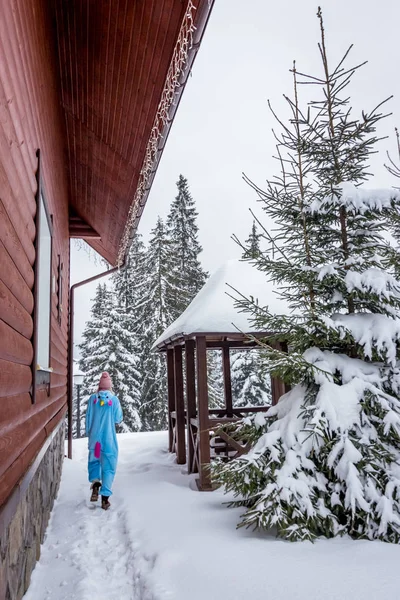 Kız mavi kar dağlarda Kayak rapordaki pembe tek boynuzlu at pijama kigurumi önünde ahşap açık evler.